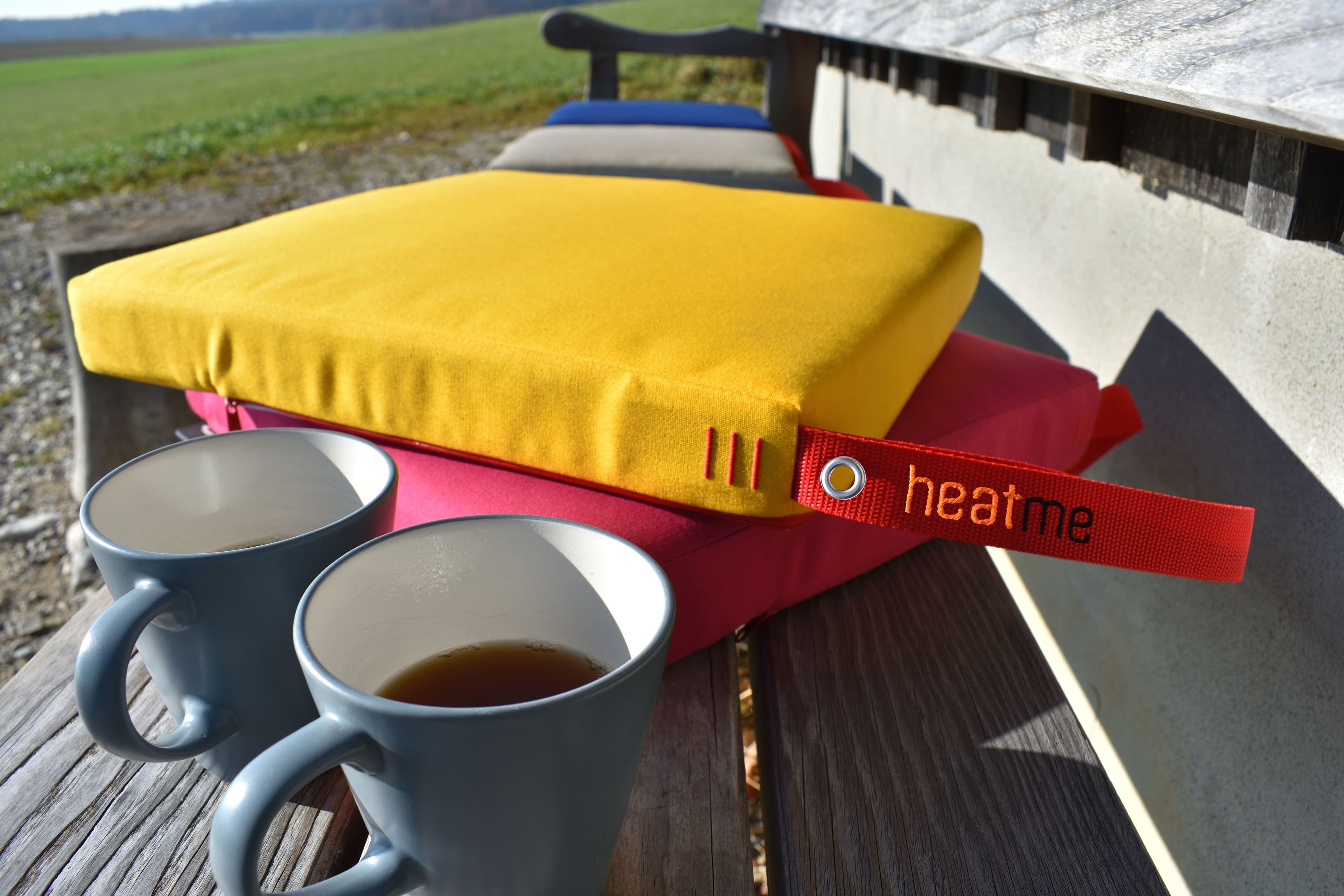 Zwei Kaffeetassen neben heatme Classic Kissen — Wärme draußen genießen