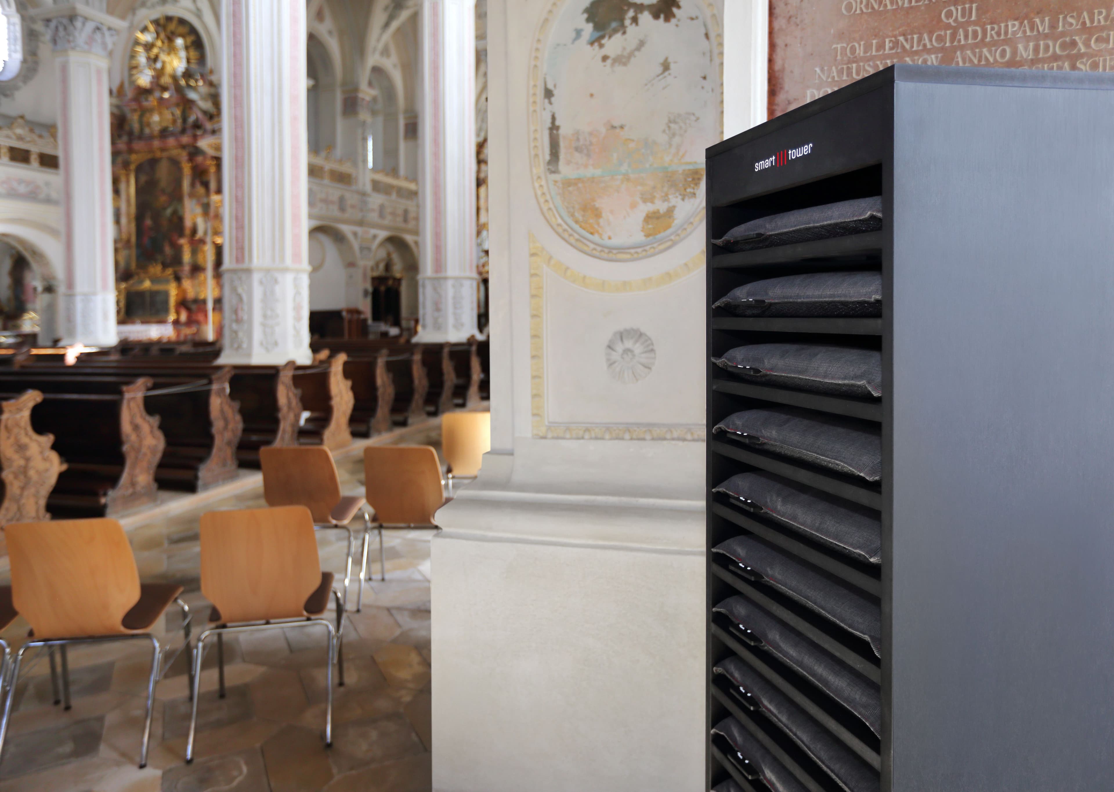 heatme Smart Tower mit Heizkissen in einer barocken Kirche – echte Installation